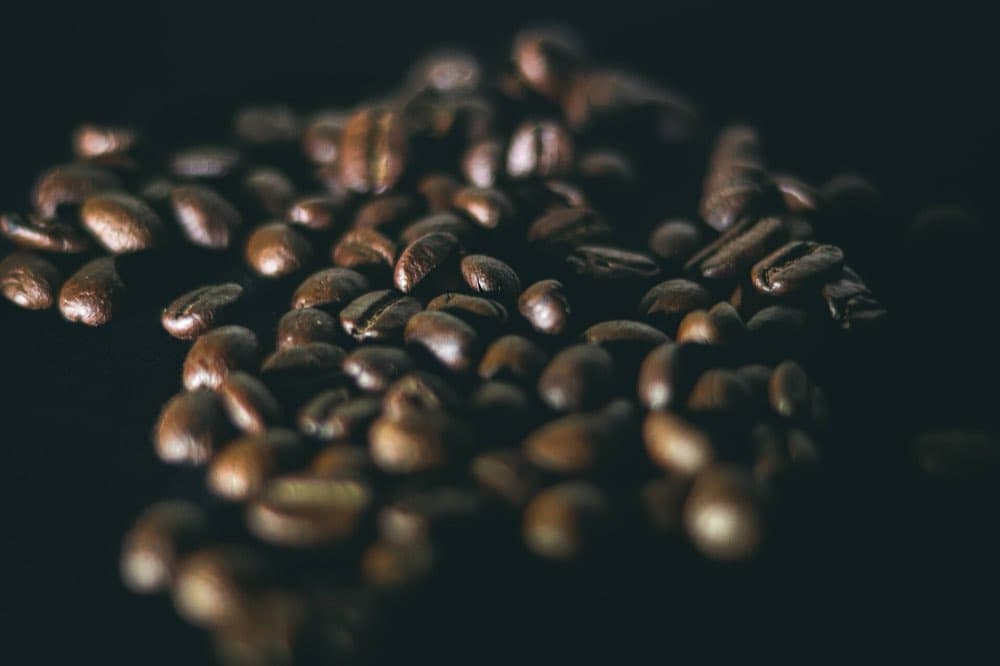 Grãos de café torrados em close, sobre fundo escuro